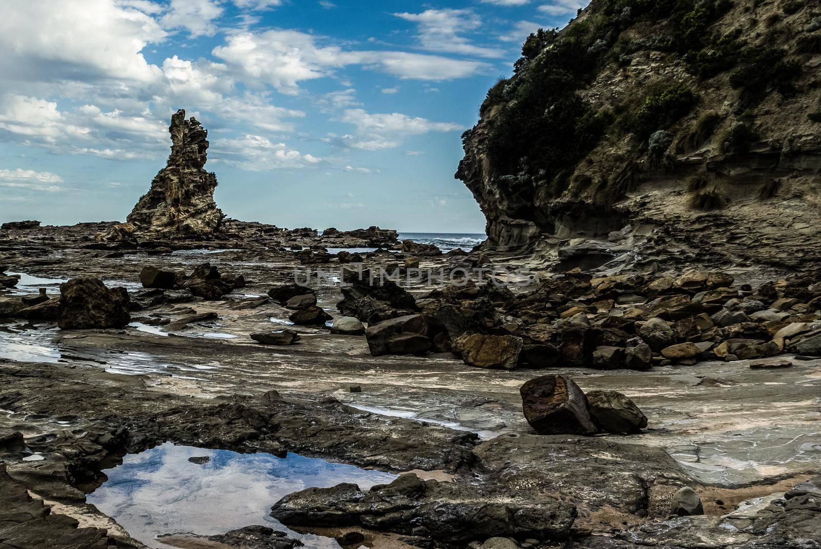 sharp and rough cliff rocks emerging from the water of the Australian coast line by bettercallcurry