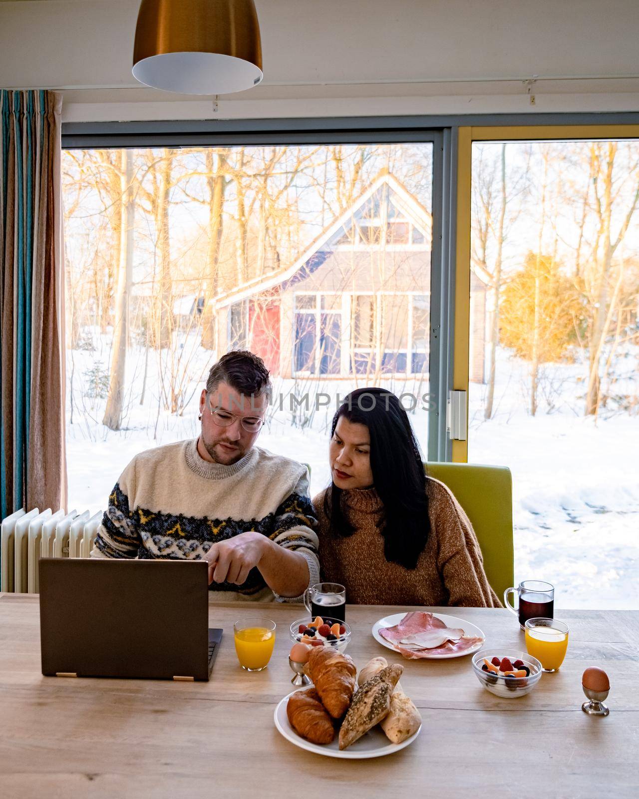 Young couple morning breakfast with laptop.Love,happiness,people and fun working from home concept by fokkebok