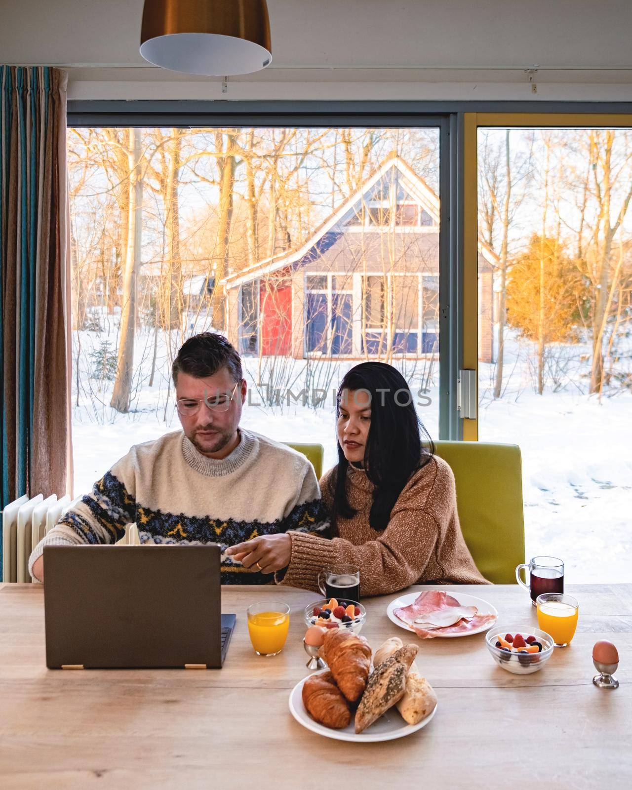 Young couple morning breakfast with laptop.Love,happiness,people and fun working from home concept by fokkebok