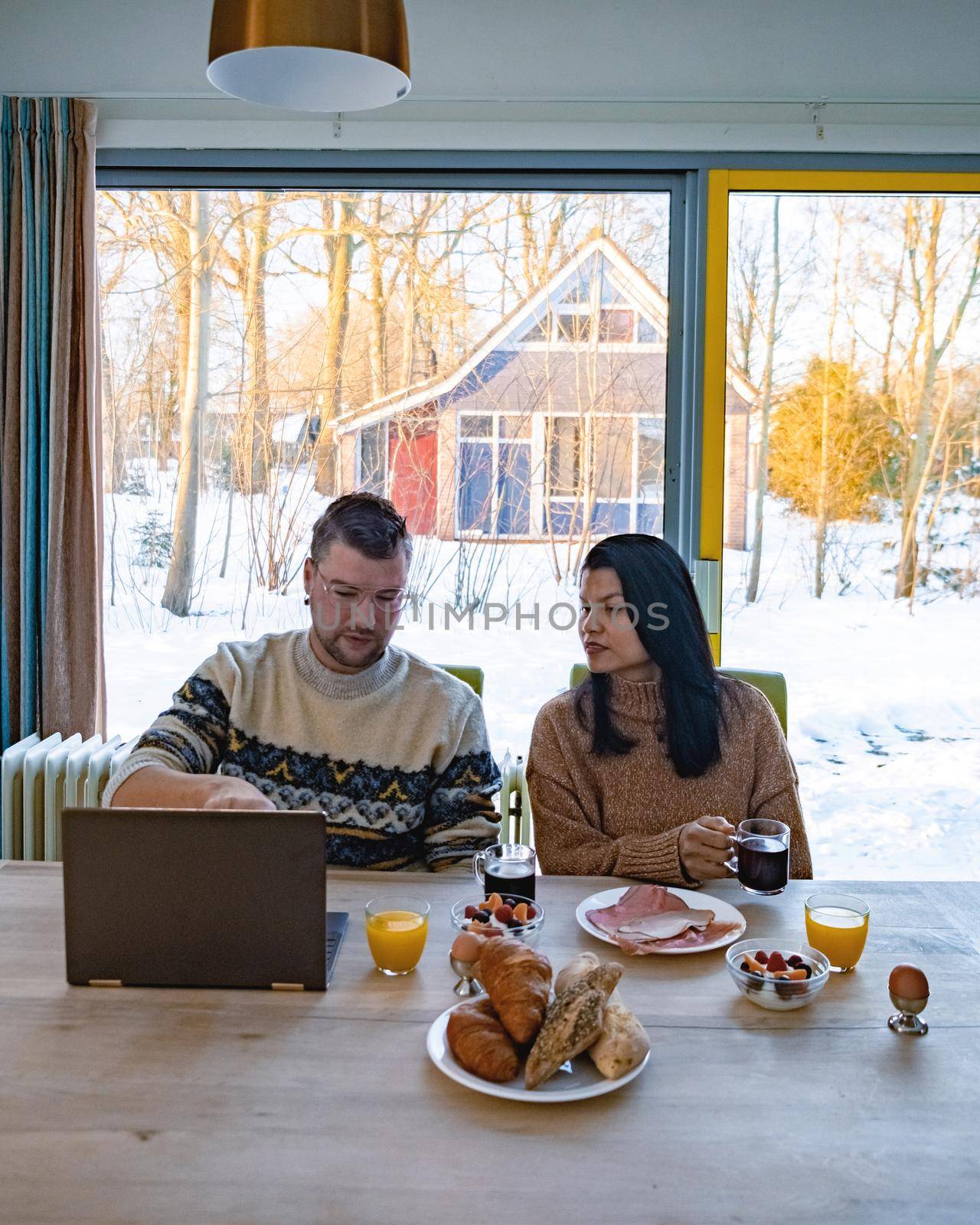 Young couple morning breakfast with laptop.Love,happiness,people and fun working from home concept by fokkebok