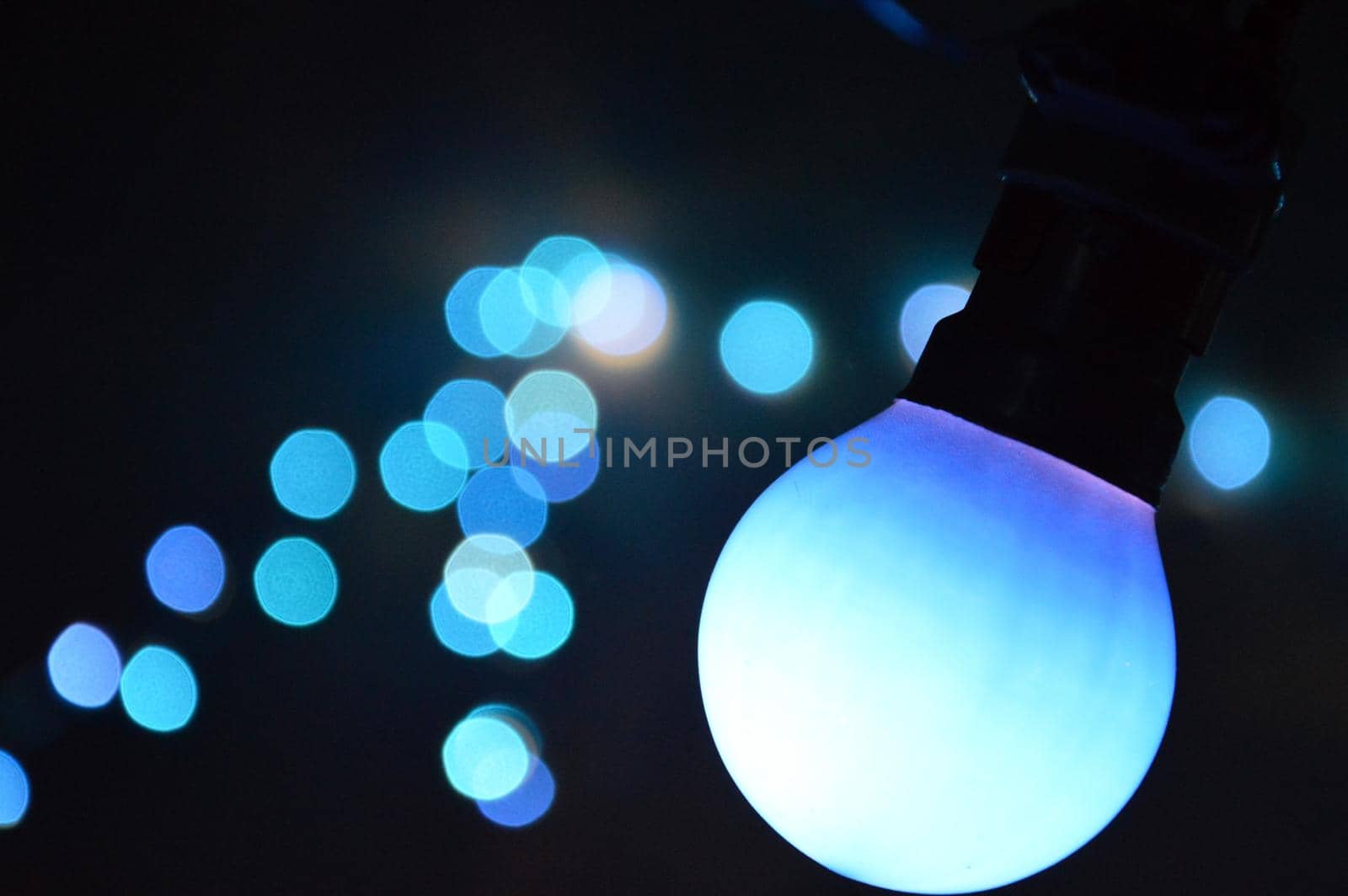 Hanging blue retro light bulb bokeh at night.