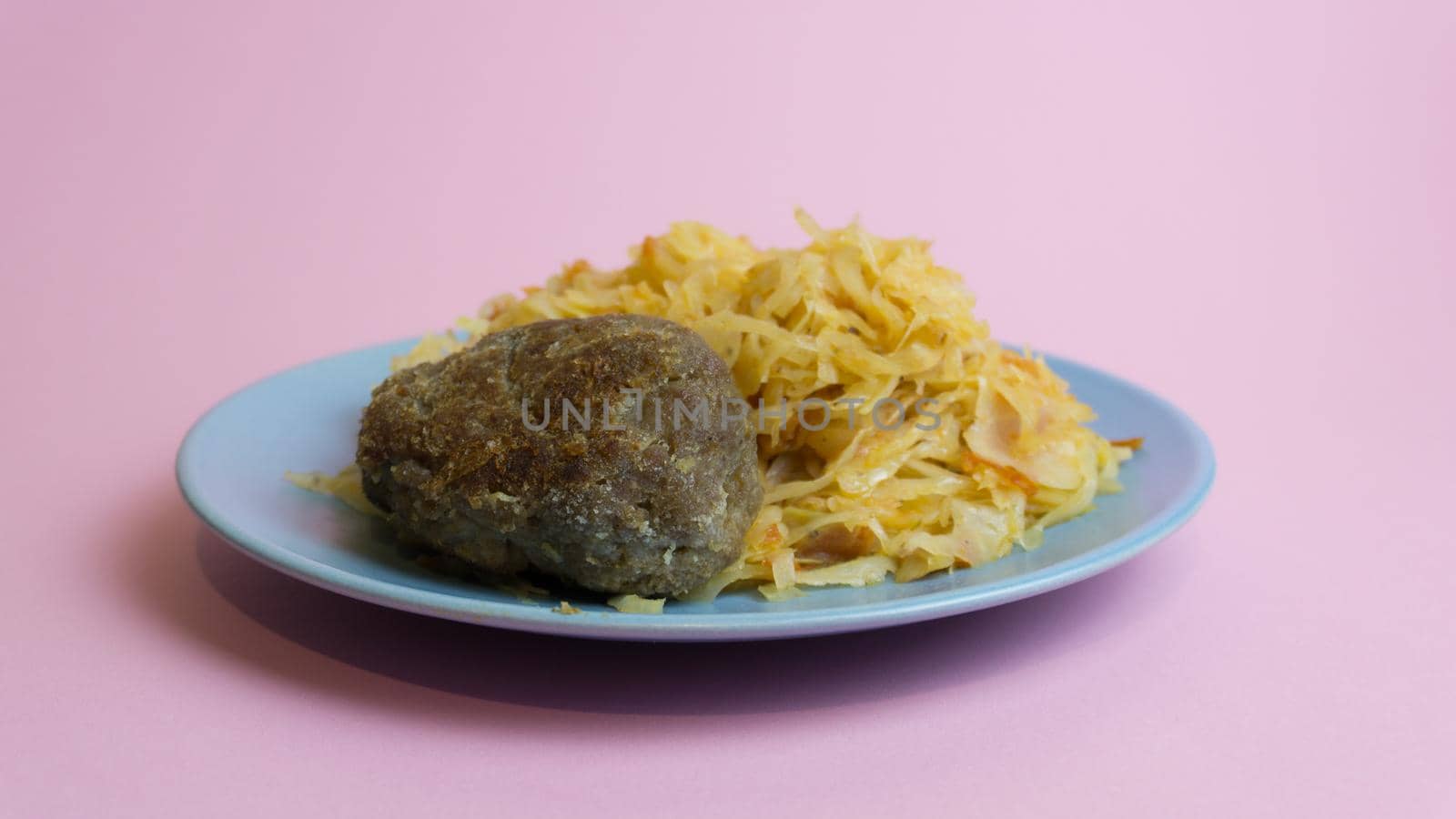 Stewed white cabbage with a cutlet steak on a plate. A dish of Russian cuisine. Garnish in the USSR.