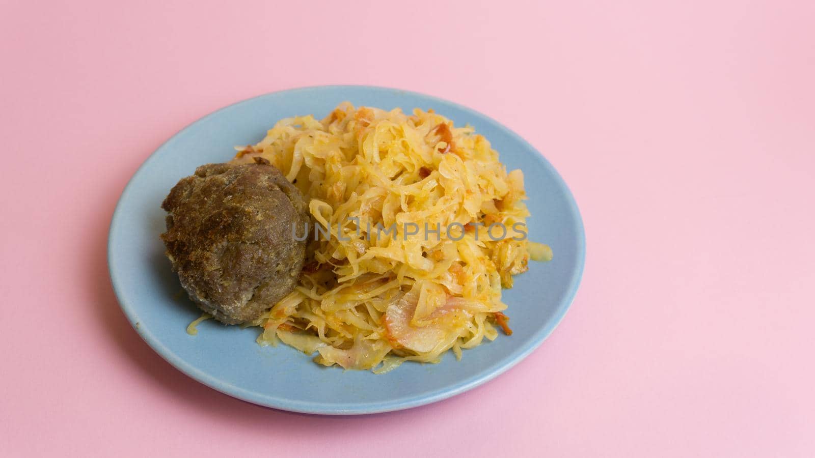 Stewed white cabbage with a cutlet steak on a plate. A dish of Russian cuisine. Garnish in the USSR.