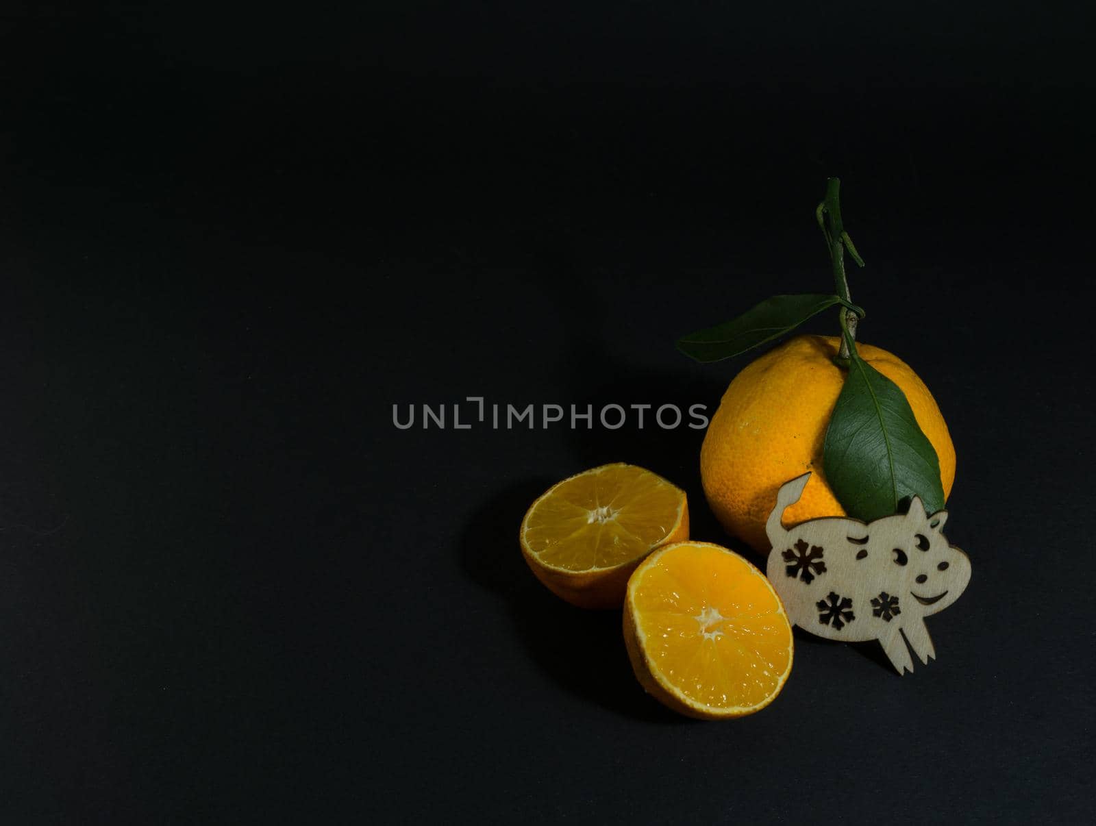 Tangerine cut with a green leaf on a black background Goby symbol of 2020