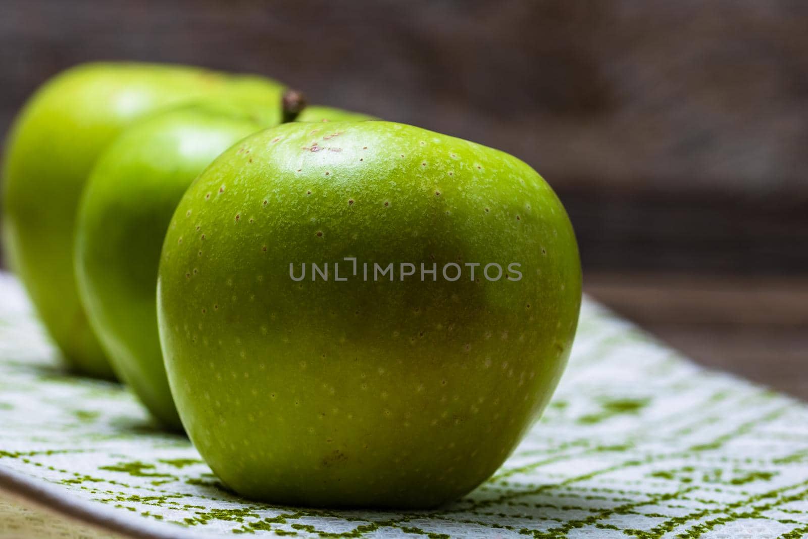 Detail on ripe green apples on wooden table. by vladispas