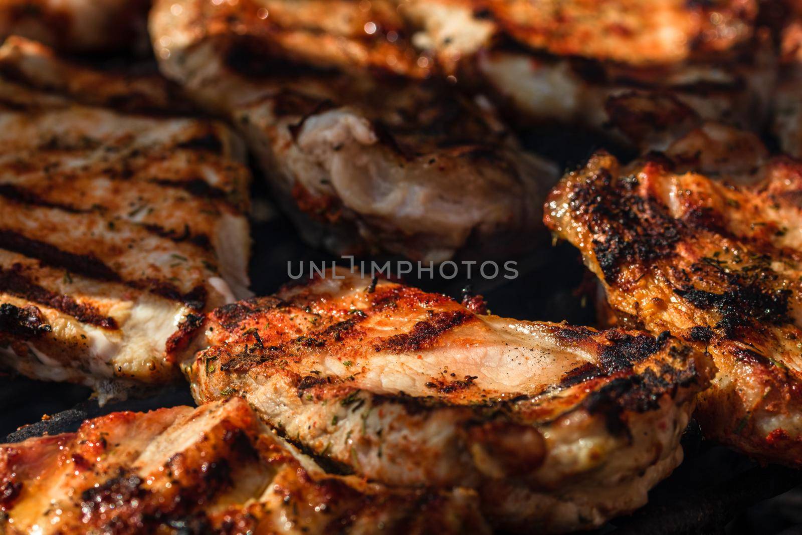 Grilling pork steaks. Delicious meat steaks close up cooking on the barbecue grill by vladispas