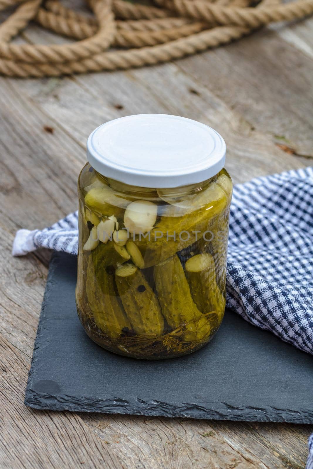 Close up of glass jar with pickles isolated. Preserved food concept, canned vegetables isolated in a rustic composition. by vladispas