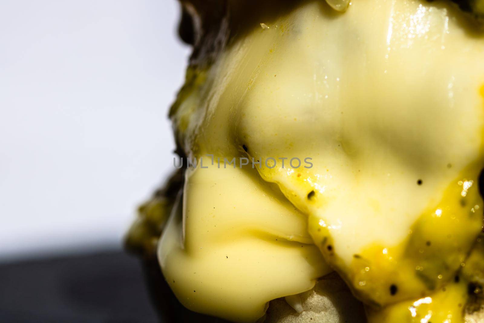 Close up of melted cheese in a homemade cheeseburger isolated on black plate.