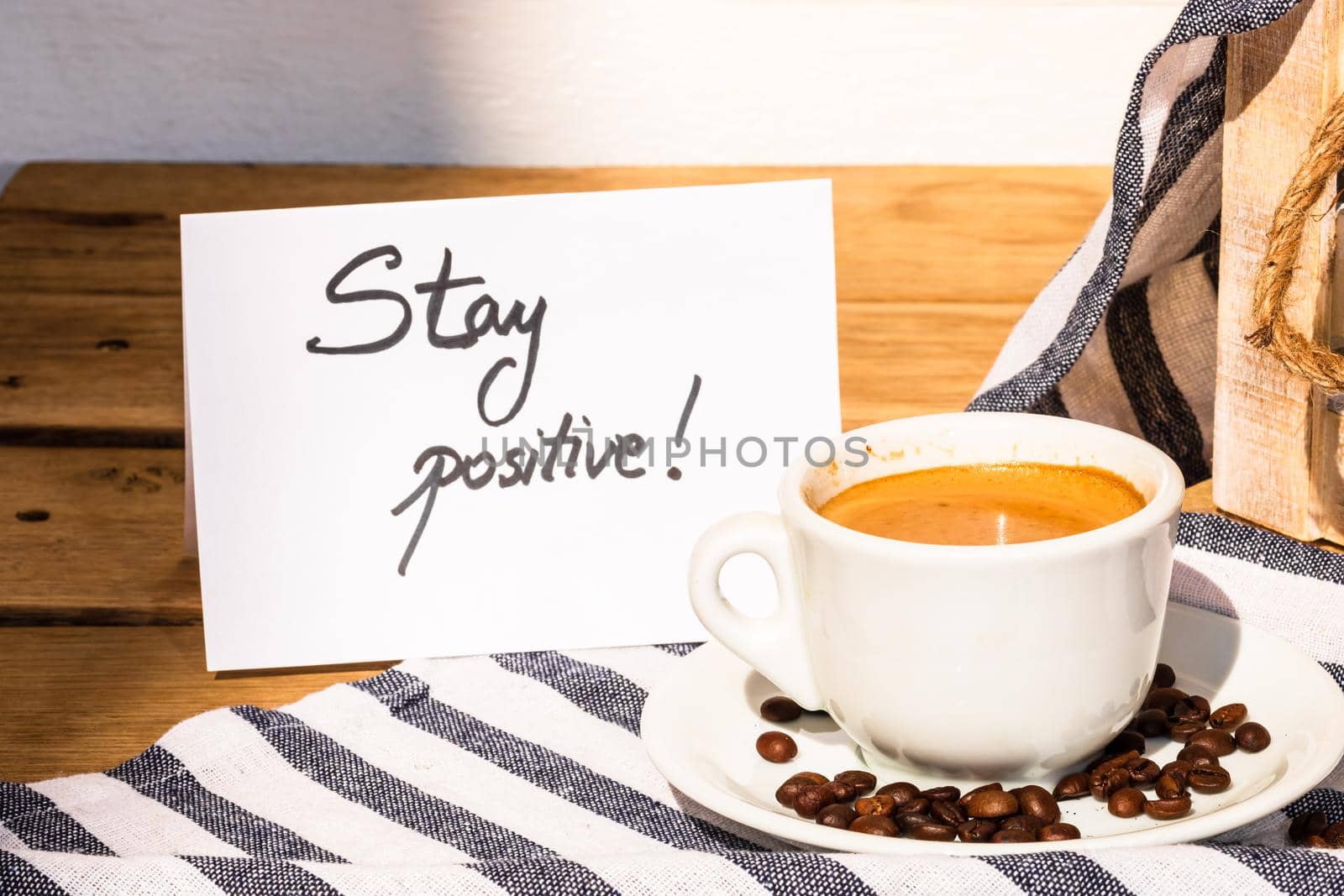 Coffee cup and buttered fresh French croissant on wooden crate. Food and breakfast concept. Morning message “stay positive” on white board