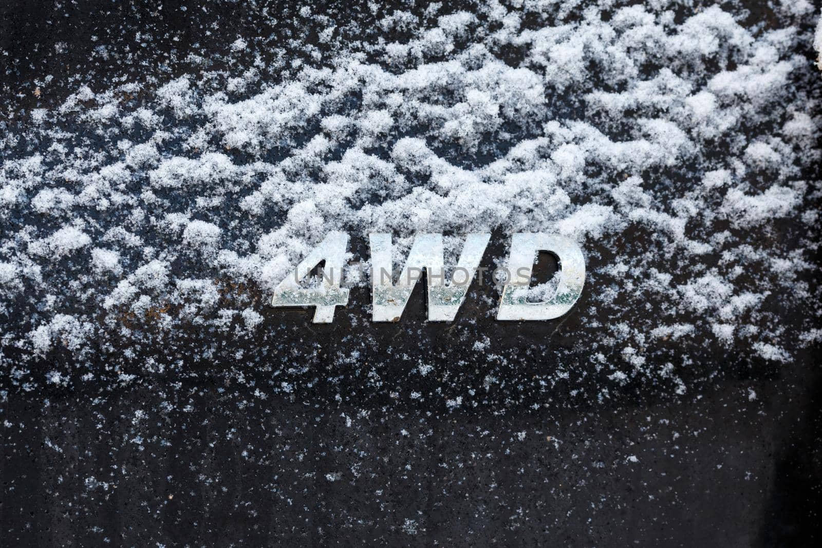 an abbreviation 4wd - four wheel drive - on dirty black car back, with snow