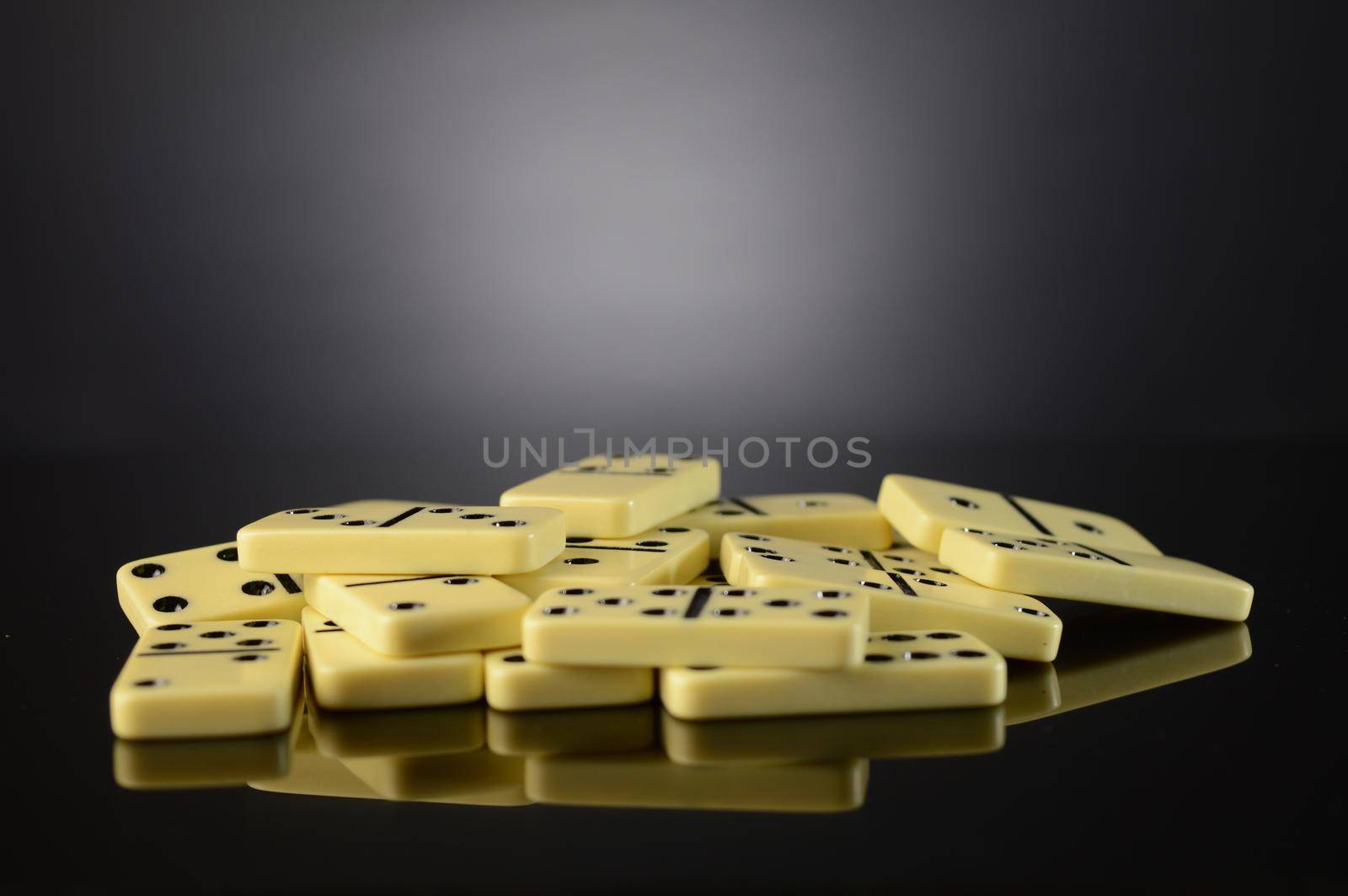 A pile of dominoes over a dark reflective surface.
