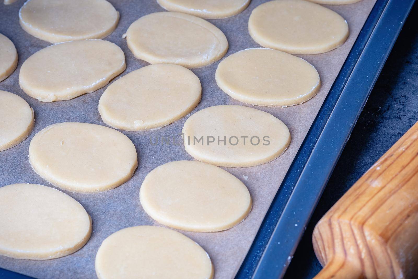 Woman prepares butter cookies at home in the kitchen, the table is sprinkled with flour, rolls out the dough, cuts out the shape, the concept of cooking festive food, christmas or easter sweets