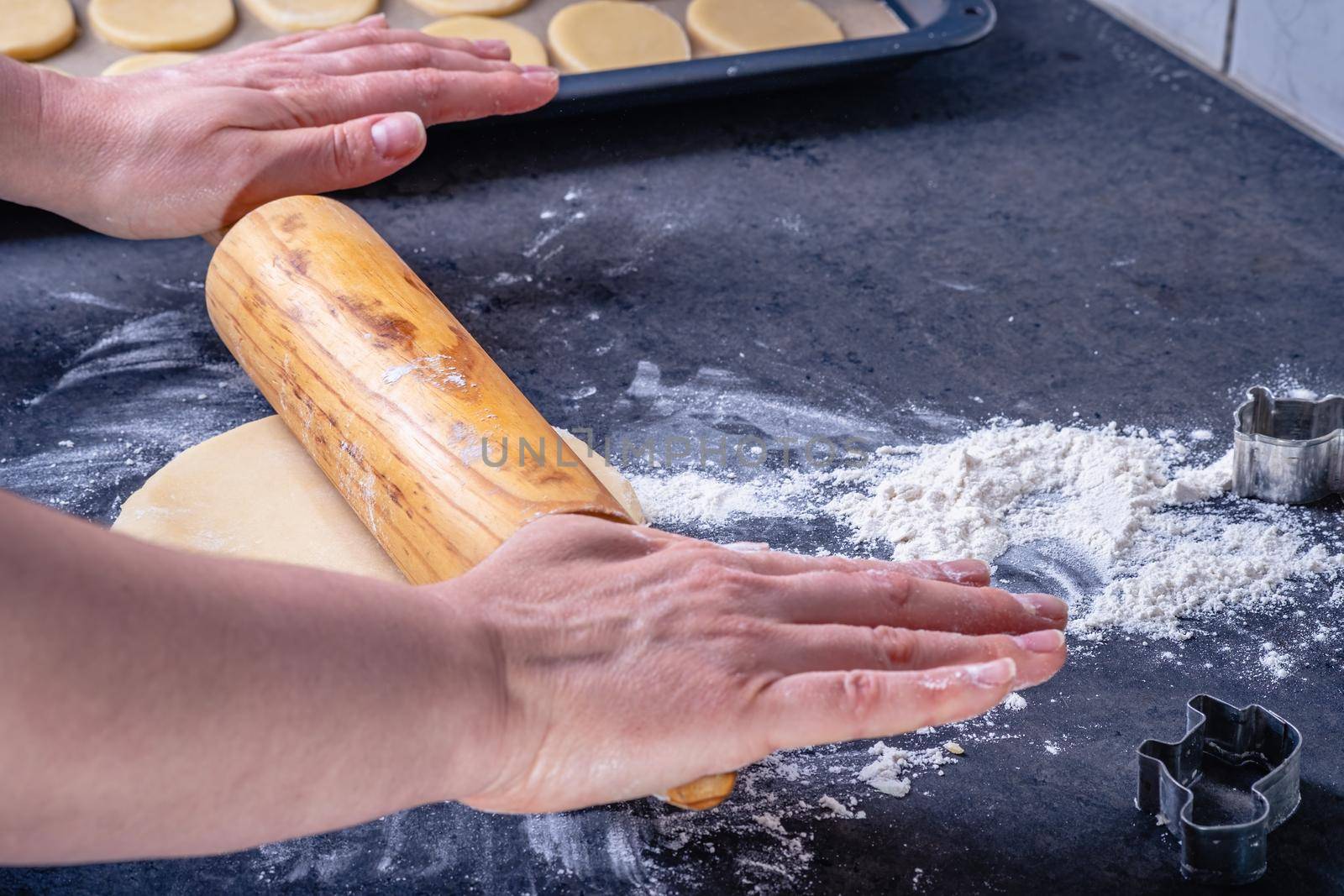 Woman prepares butter cookies at home in the kitchen by Fischeron