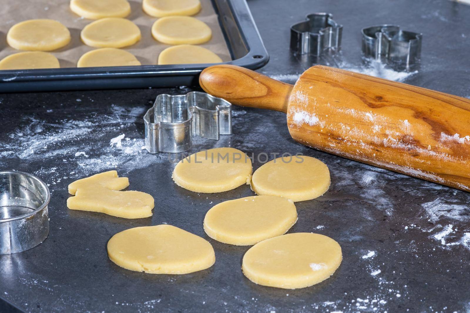 Rolling pin and kitchenware for making easter cookies on dark background.