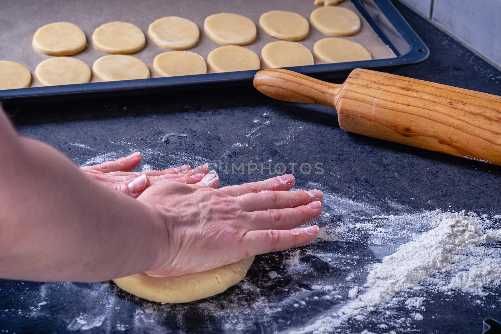 Woman prepares butter cookies at home in the kitchen by Fischeron