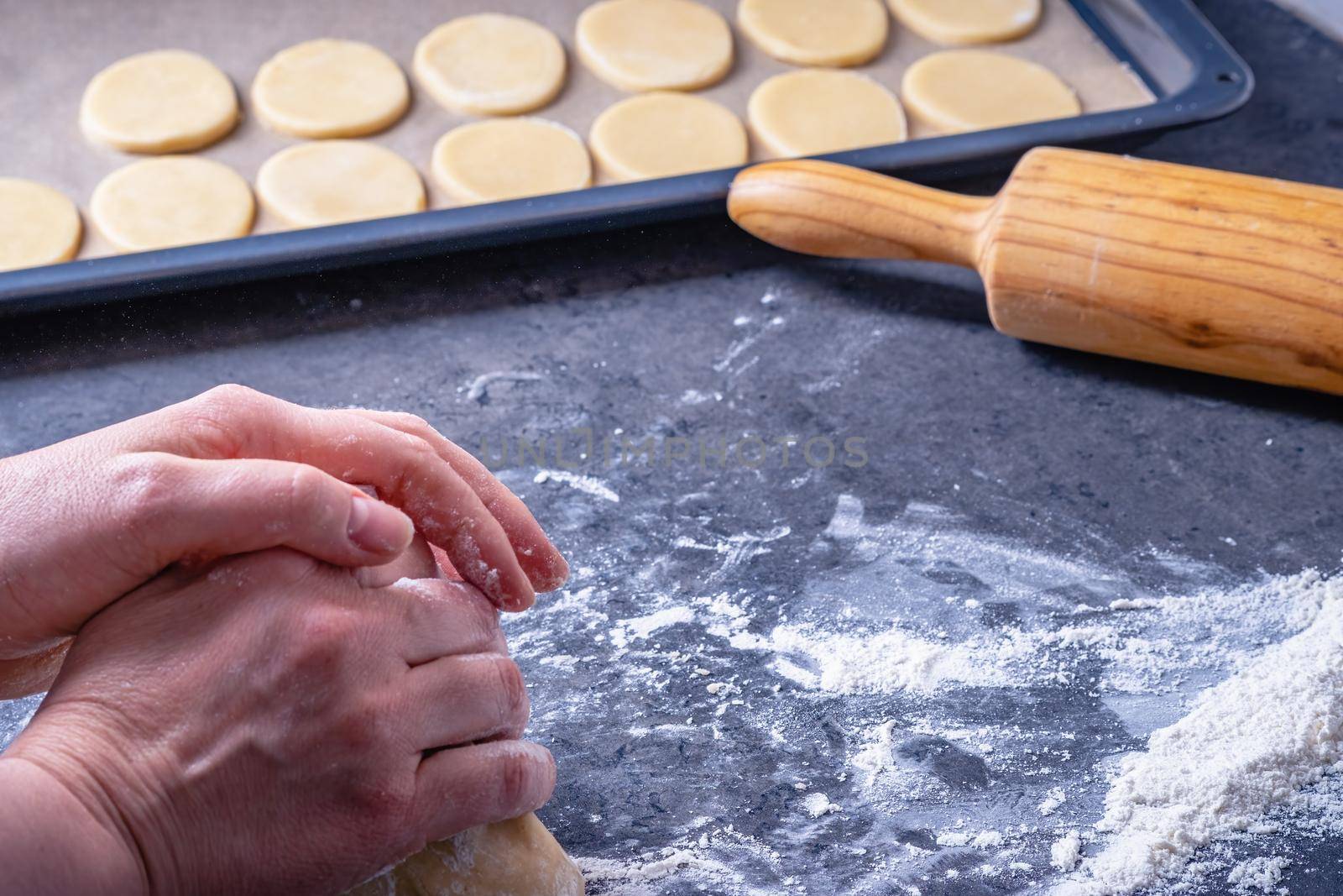 Woman prepares butter cookies at home in the kitchen by Fischeron