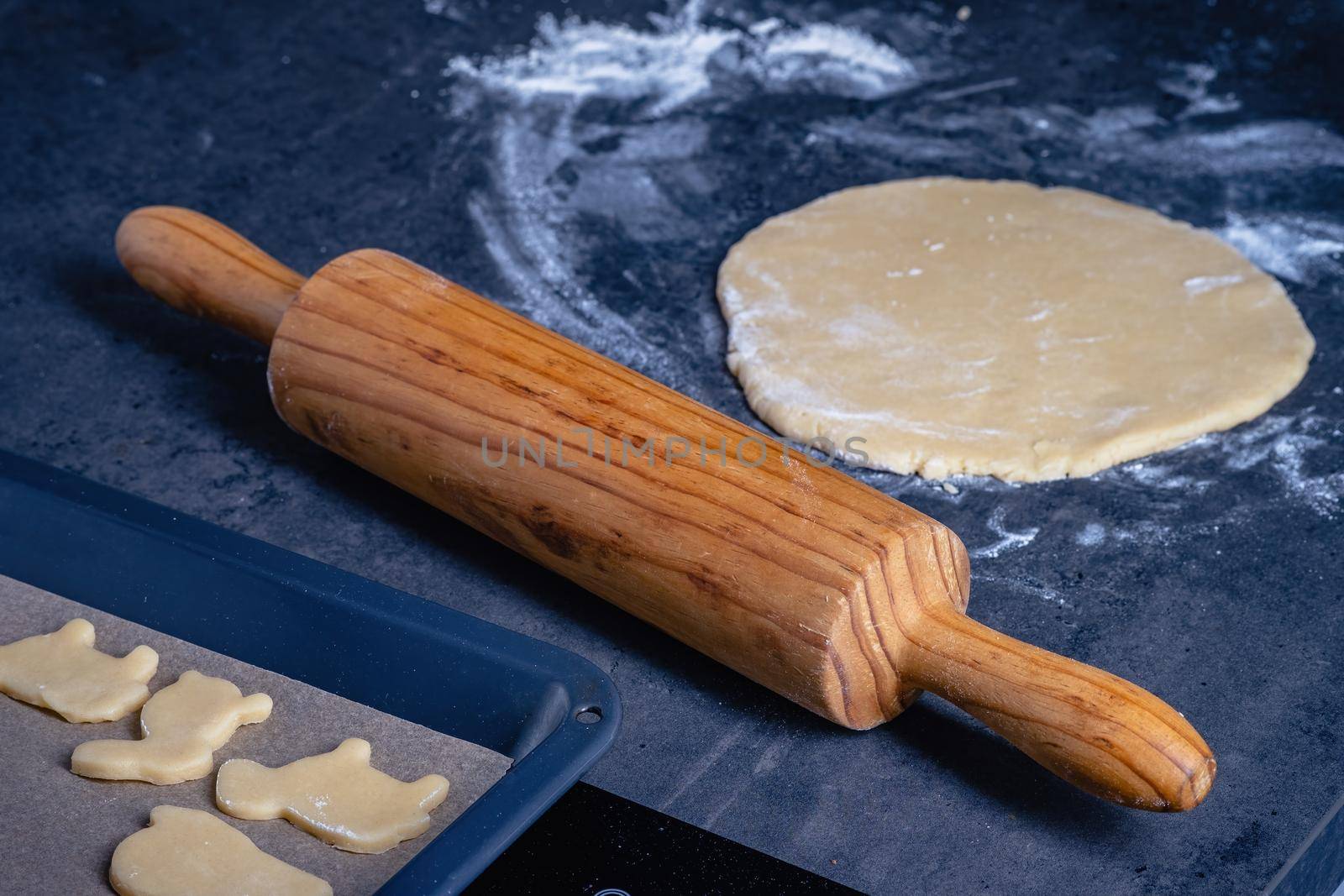 Rolling pin and kitchenware for making easter cookies on dark background.