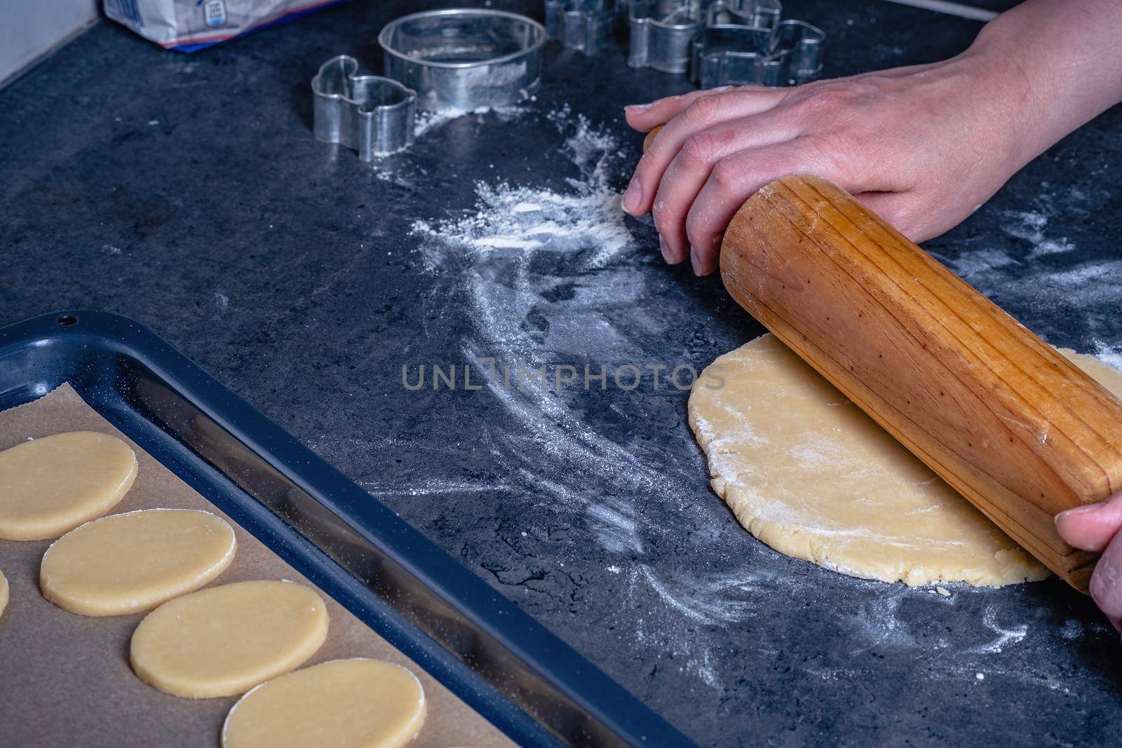 Woman prepares butter cookies at home in the kitchen by Fischeron