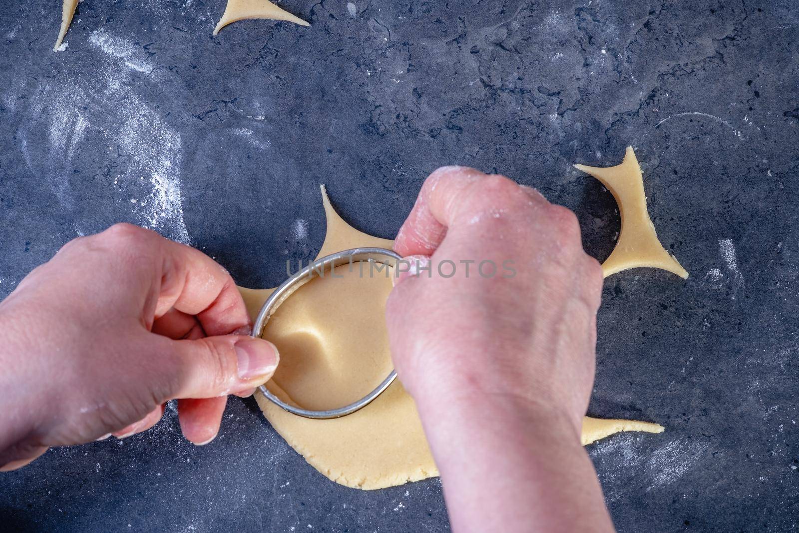 Woman prepares butter cookies at home in the kitchen by Fischeron