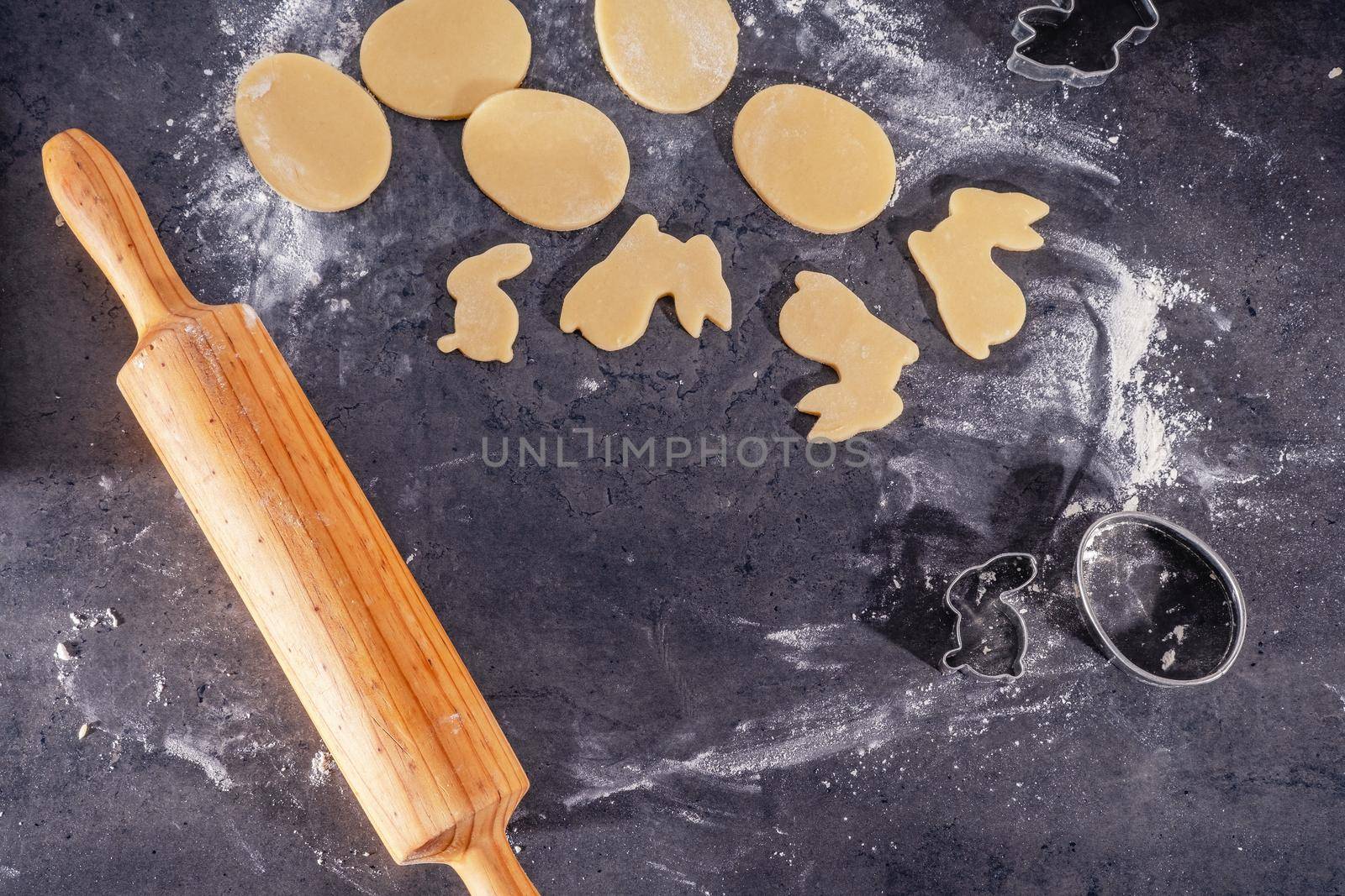 Rolling pin and kitchenware for making easter cookies on dark background.