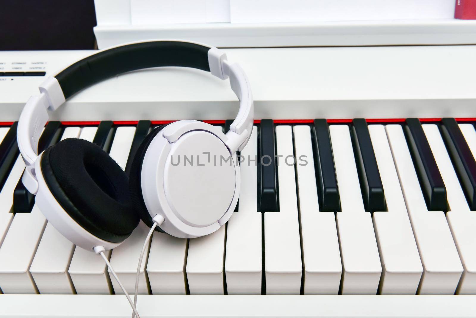 white headphones lie on the keyboard of the electronic piano by karpovkottt
