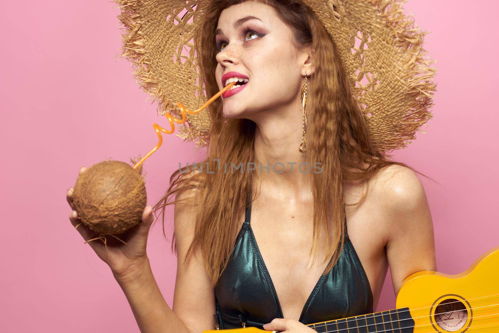 Woman holding ukulele coconut cocktail beach hat Exotic lifestyle swimsuit pink background by SHOTPRIME