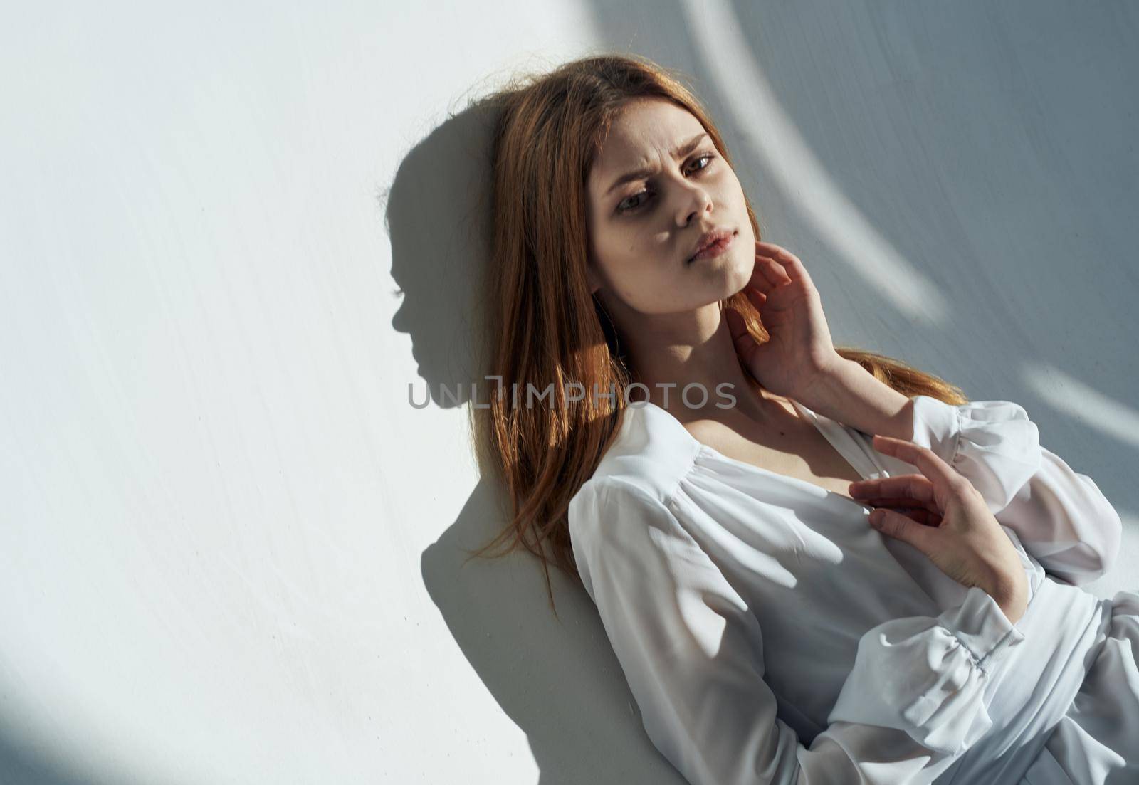 Woman on a light background in white clothes makeup red hair. High quality photo
