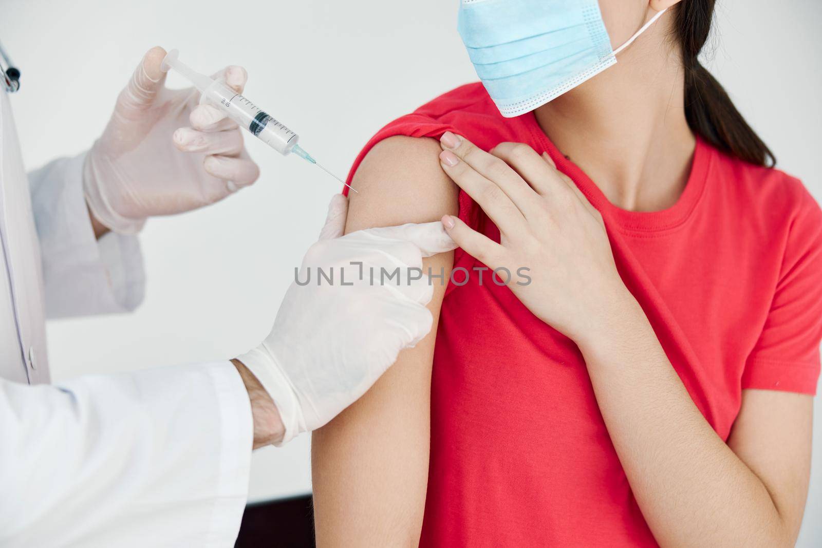 a doctor with a syringe in his hand makes an injection in the shoulder health covid vaccination health care by SHOTPRIME