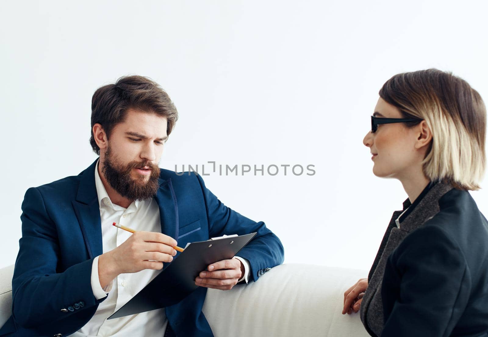 Business man with documents explains something to a young woman Sitting on a sofa indoors. High quality photo