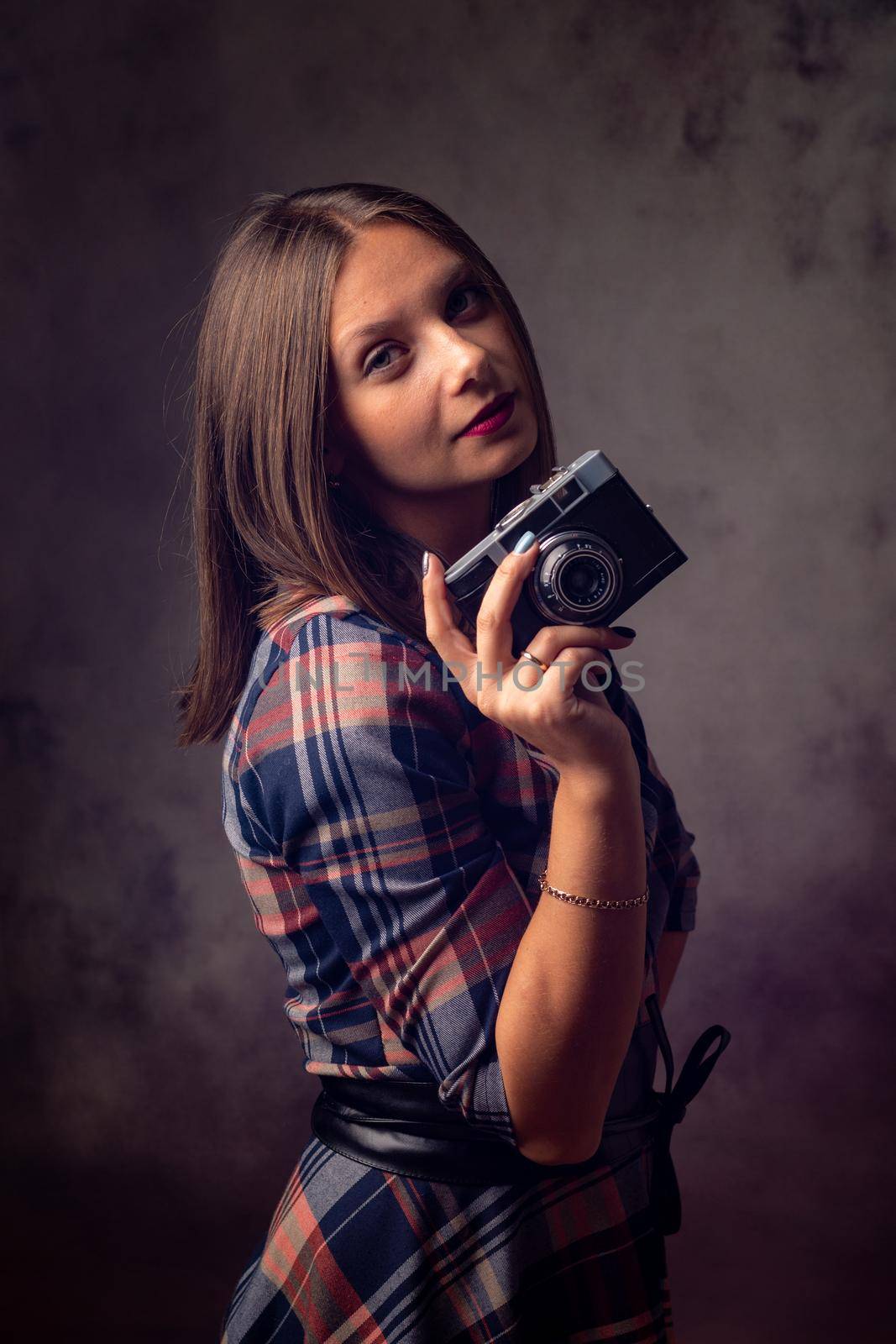 Girl photographer with retro camera, studio photography on gray background
