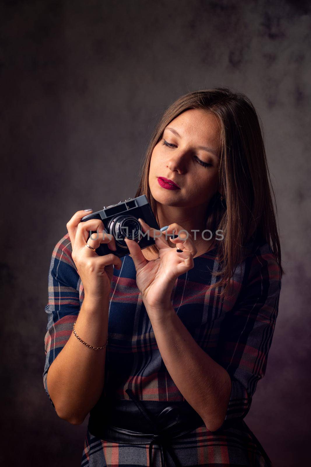 Girl photographer adjusts the camera, studio photography on a gray background by Madhourse