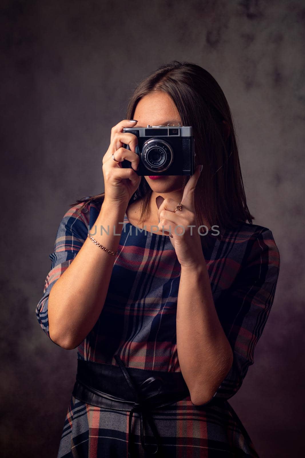 Girl photographer takes pictures with an old camera, studio photography on a gray background by Madhourse