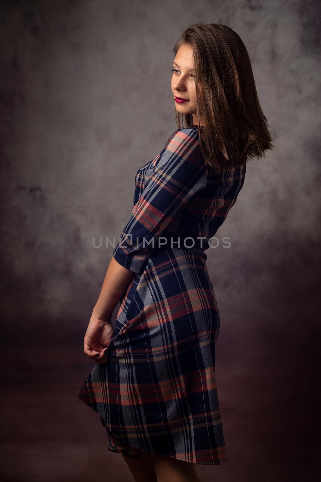 Portrait of a beautiful girl in a checkered dress, the girl is turned sideways