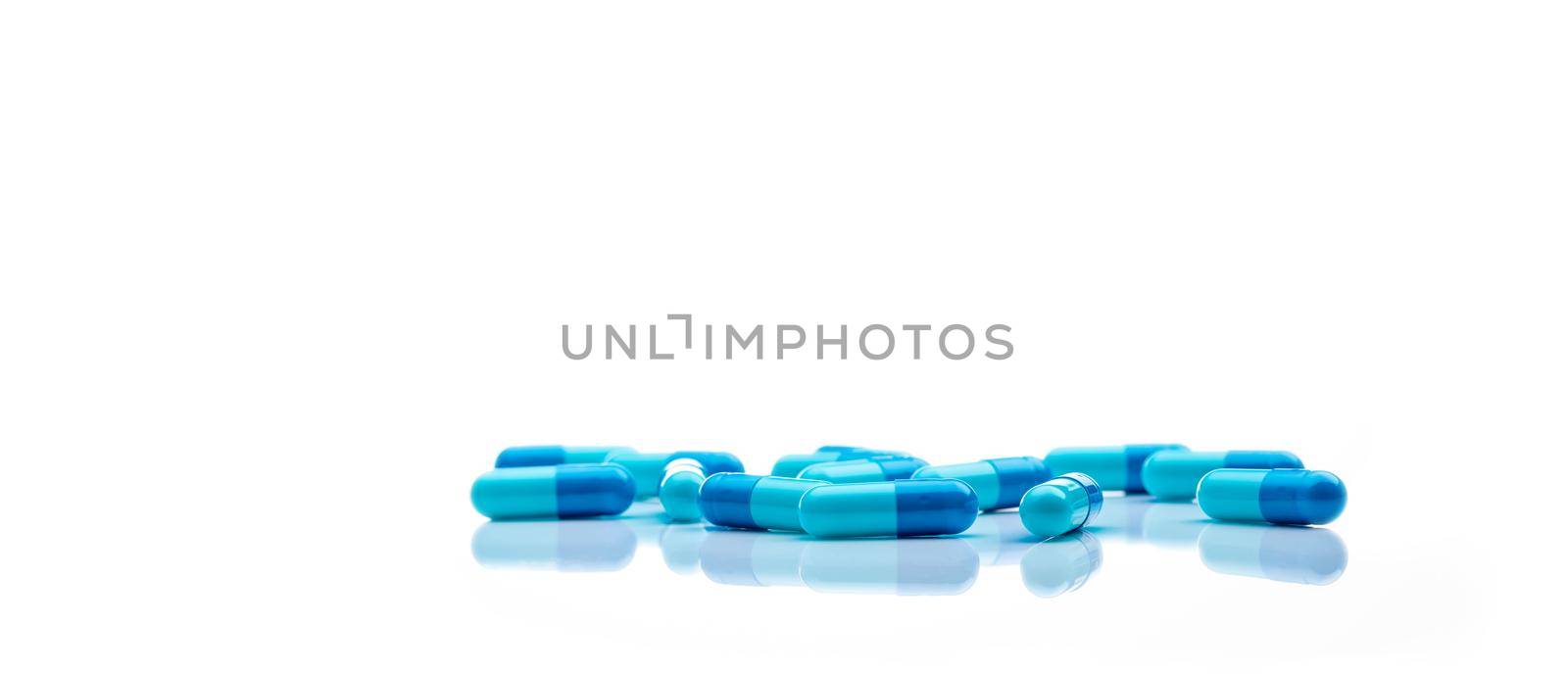 Blue antibiotic capsule pills spread on white background. Antibiotic drug resistance. Pharmaceutical industry. Healthcare and medicine concept. Health budget concept. Capsule manufacturing industry.