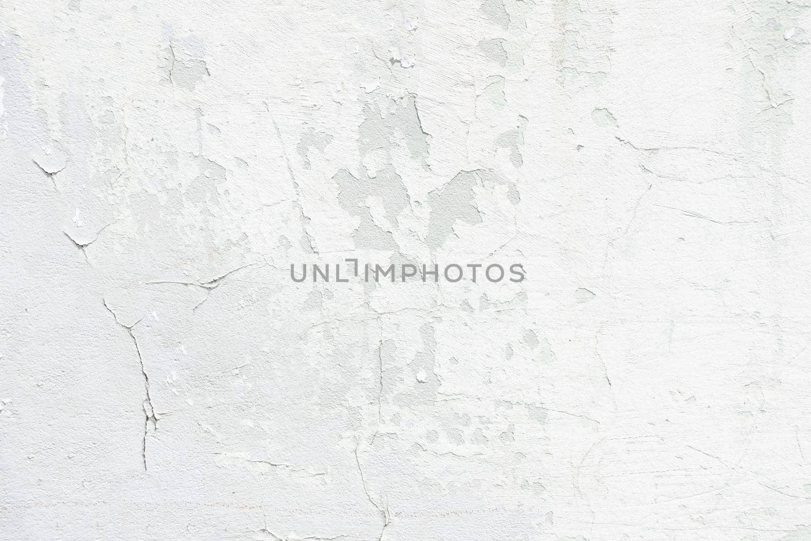 Outdoor concrete white wall with cracked and flaked surface close up
