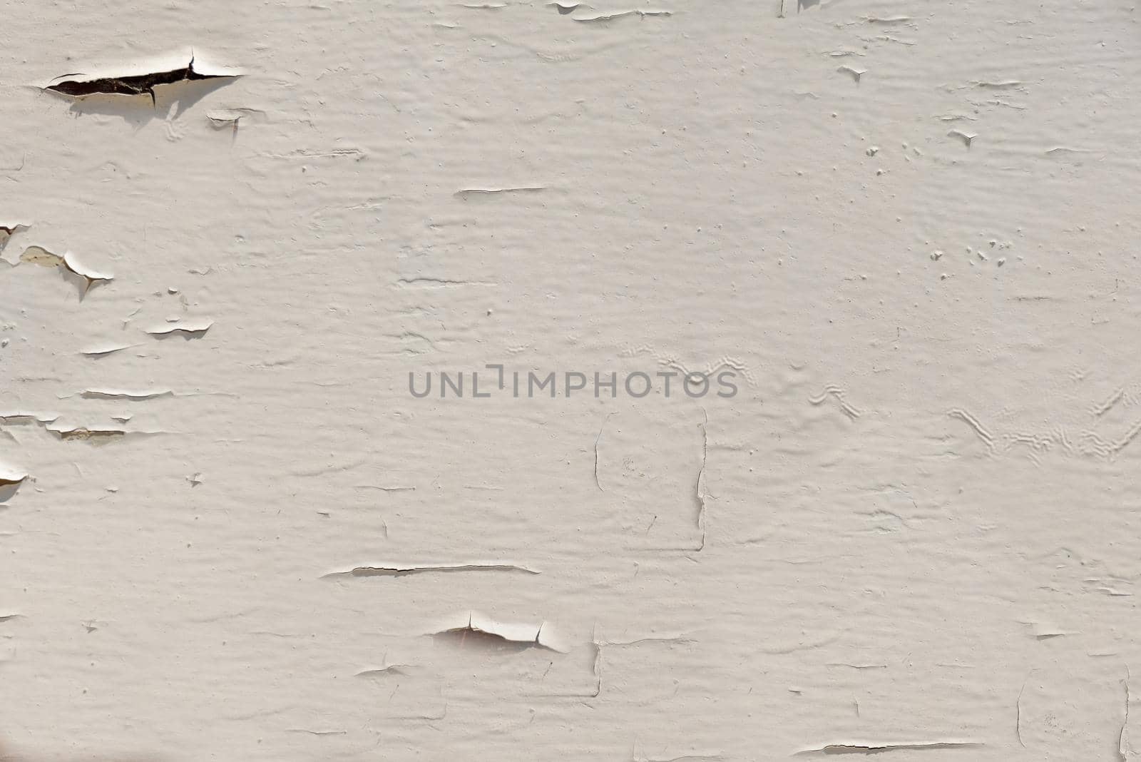 Outdoors, beige paint flakes off the surface of the wall in close-up.Texture or background
