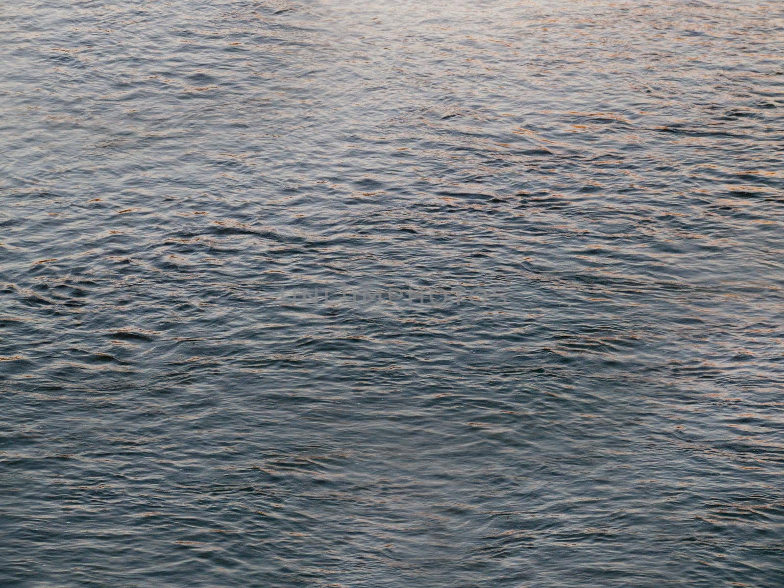 Sea water small waves close-up dark blue color.Texture or background