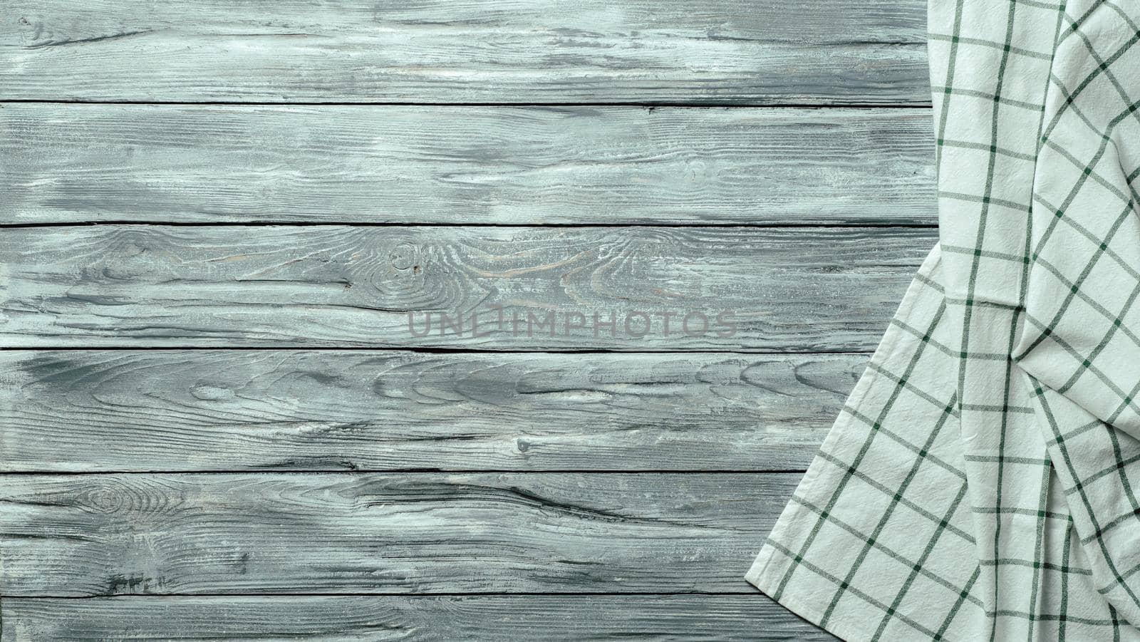 Gray wooden table with linen kitchen towel or textile napkin flat lay. Blue tablecloth on old gray wood tabletop. Copy space for text. Can use as mock up for design.