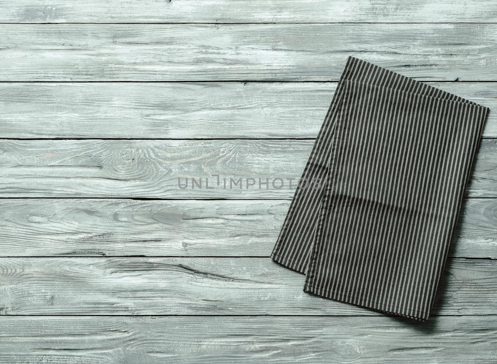 Gray wooden table with balck and white dark linen kitchen towel or textile napkin flat lay. Dark tablecloth on old gray wood tabletop. Copy space for text. Can use as mock up for design.