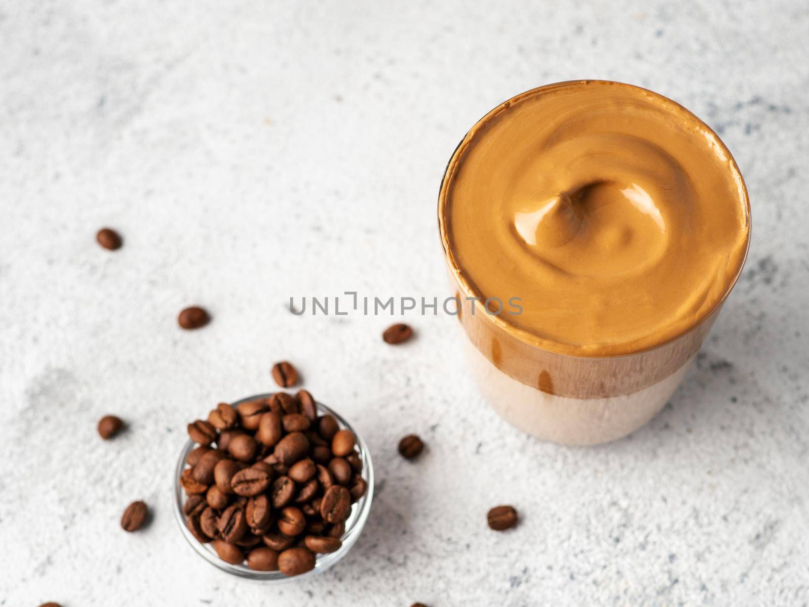 Trendy korean drink - dalgona coffee. Glass jar with cold or hot beverage - whipped instant coffee with milk on gray cement background with copy space. Top view or flat lay.