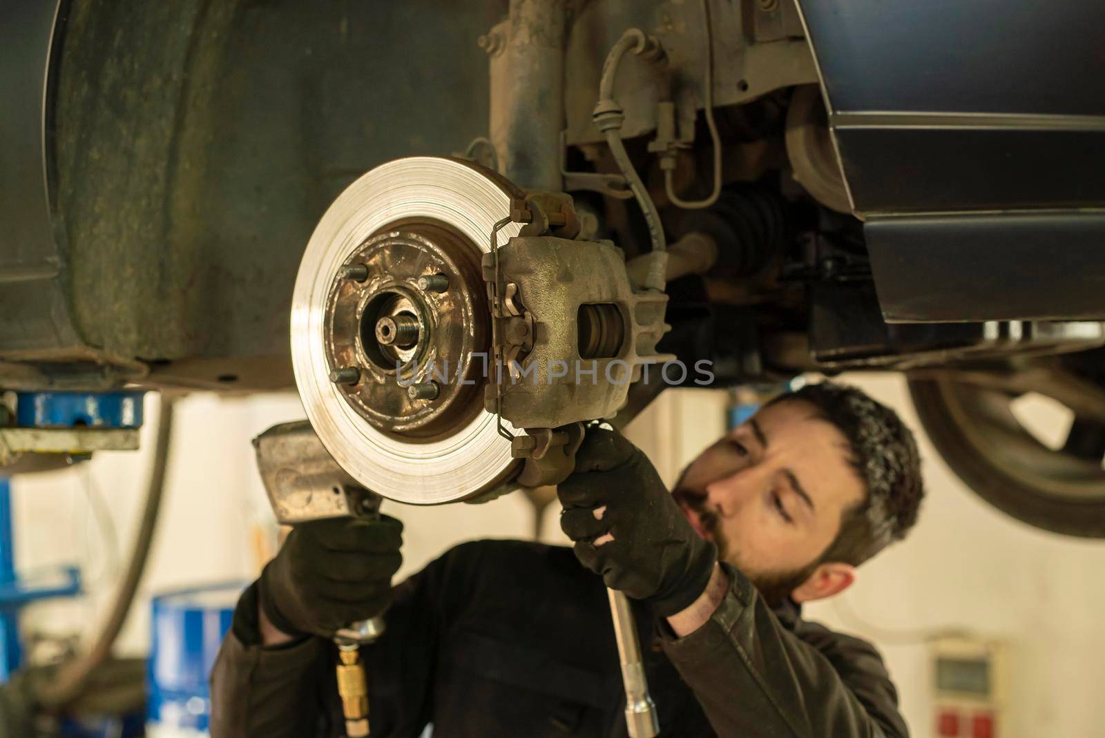 Mechanic carries out the replacement of the brakes of the car in the workshop
