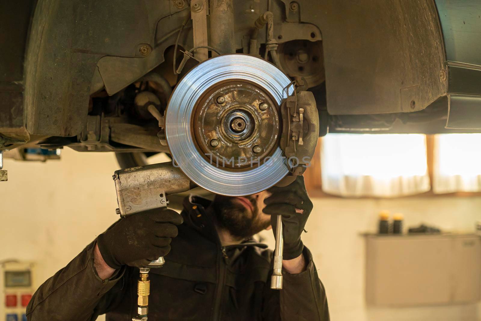 Mechanic carries out the replacement of the brakes of the car in the workshop