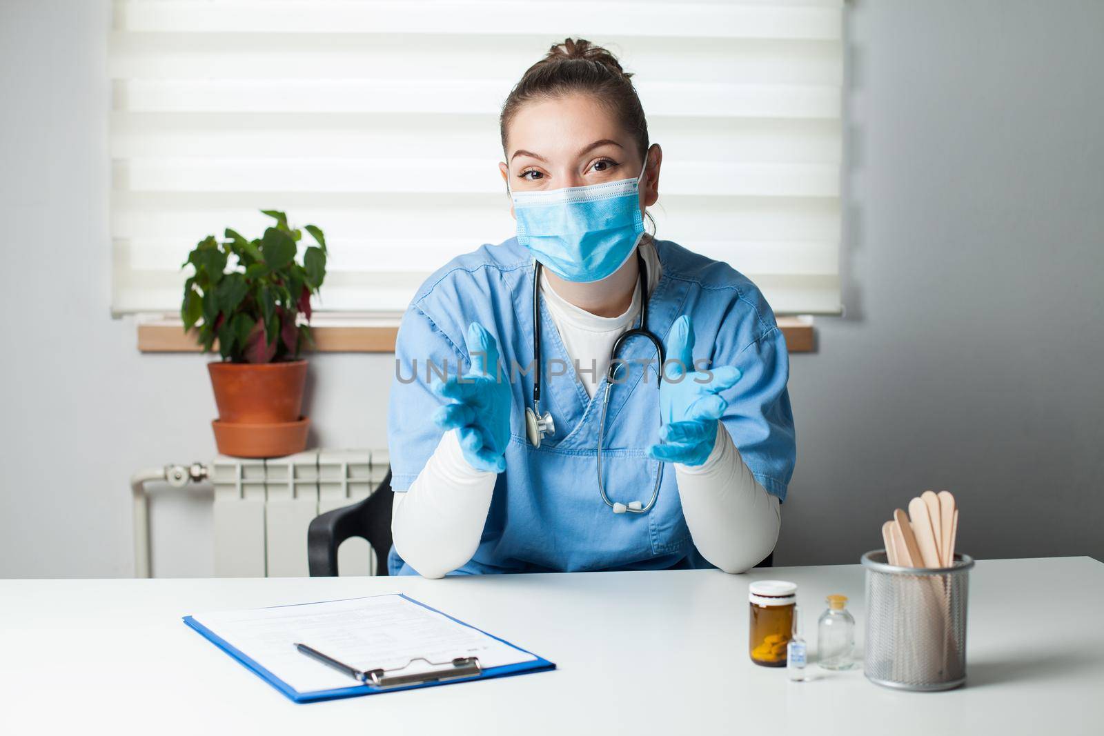 Portrait of female doctor wearing protective gloves and face mask by Plyushkin