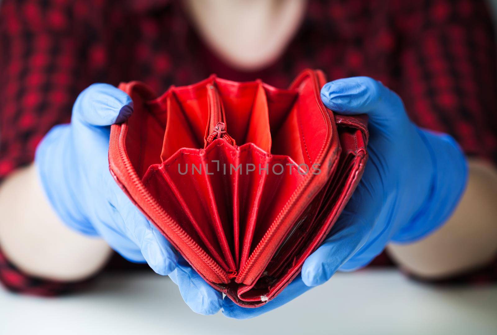 Person wearing medical protective gloves holding empty red wallet by Plyushkin