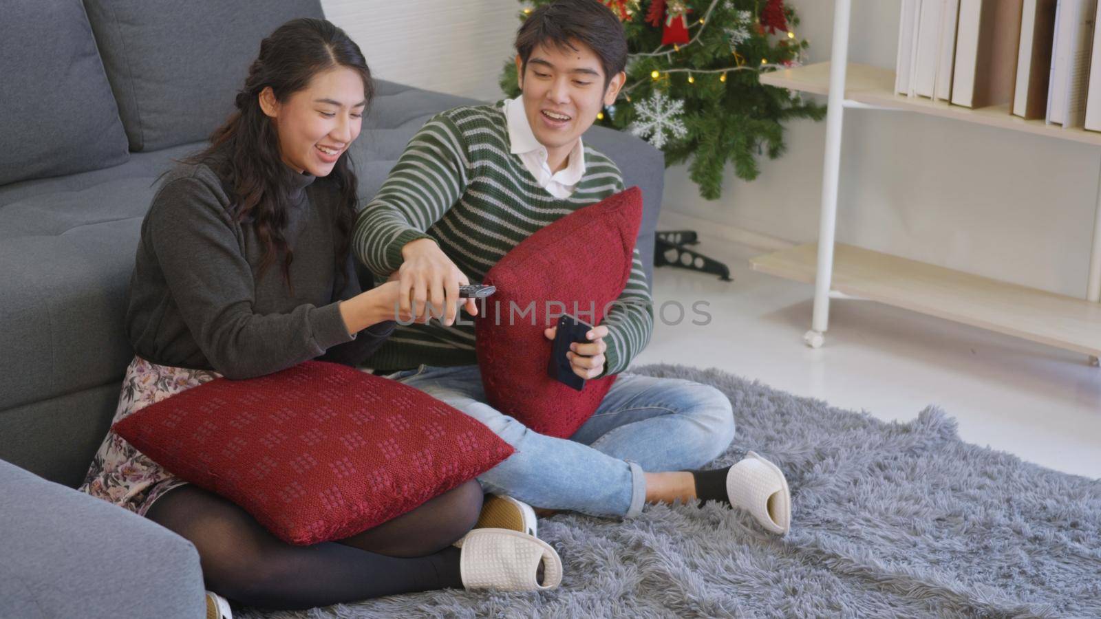 couple husband and wife enjoying winter day in living room at home watch TV television by Sorapop
