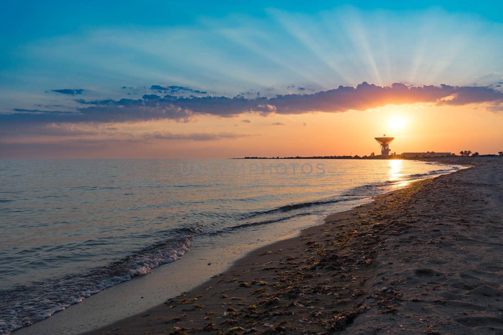 Magnificent sunset on the background of the sea and space antenna. The rays of the sunset illuminate the coastline of the sea in the area of Yevpatoria in the Crimea.
