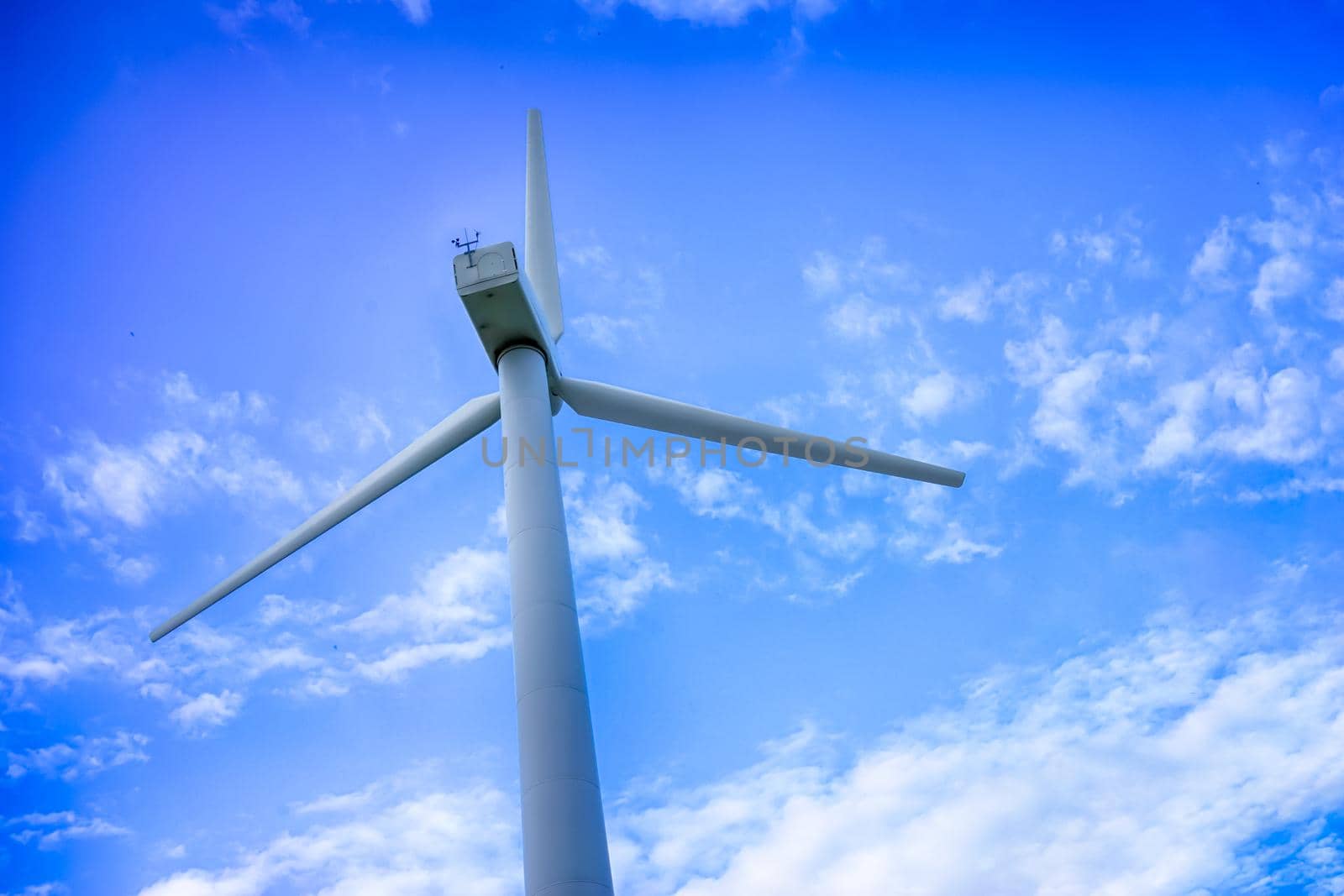 Wind power plant against a blue sky with white clouds