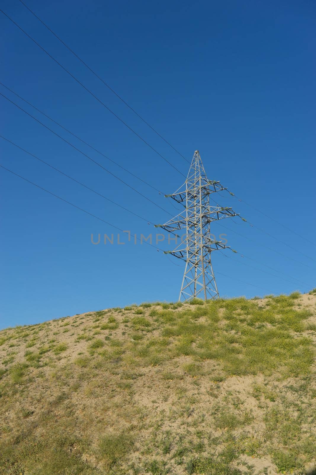 electric tower with wires on the hill against the blue sky.