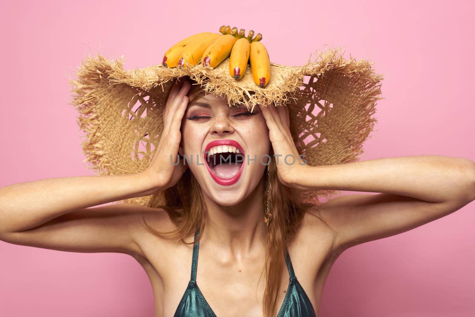 Woman in beach straw hat bananas holding fruits Exotic swimsuit pink background. High quality photo