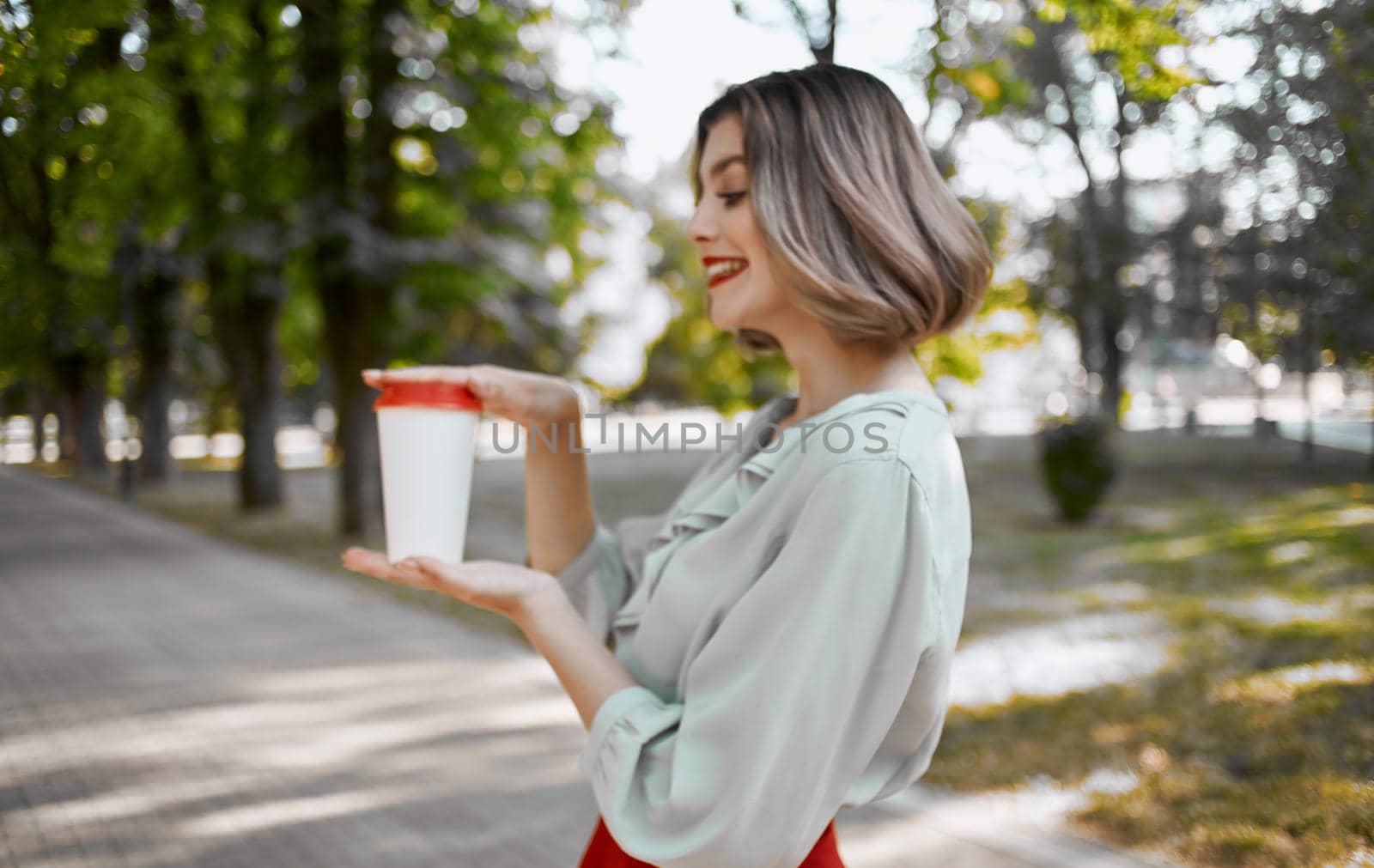 woman with a cup of drink in hand walks in the park in nature. High quality photo